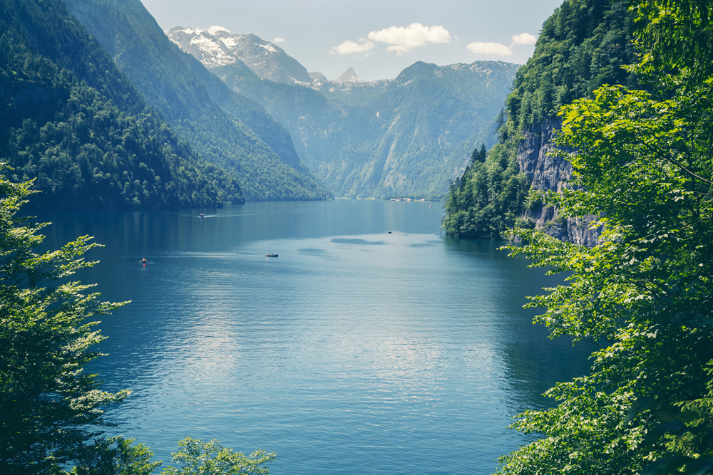 Blick auf einen tiefblauen See umgeben von steilen, bewaldeten Bergen. Im Hintergrund verschneite Gipfel. (Foto: Serkat/fotolia.com)