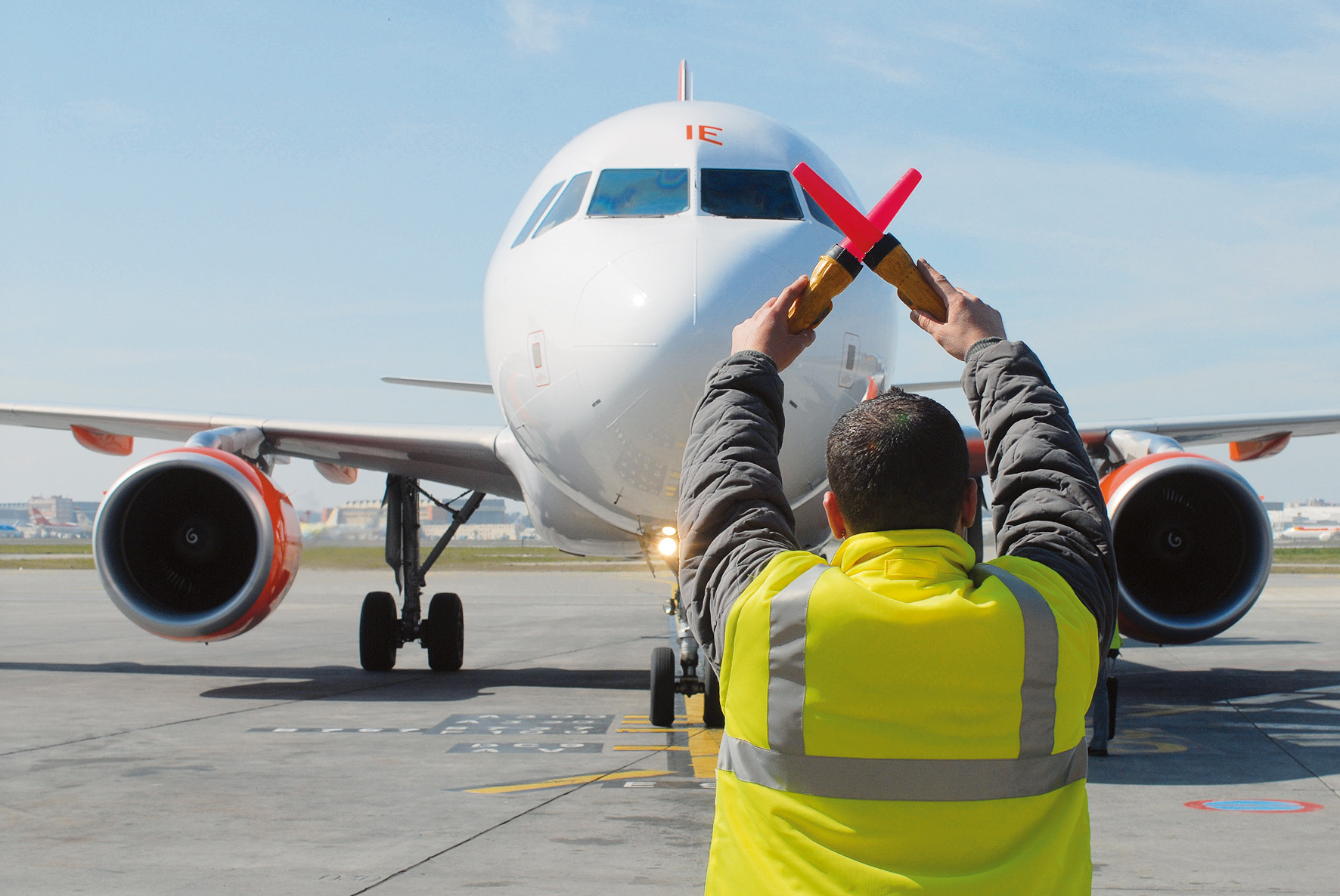 Ein Flugeinweiser bedeutet einem Flugzeug auf dem Rollfeld zu stoppen: Der Luftverkehr muss verringert werden (Foto: fotolia/nougaro)