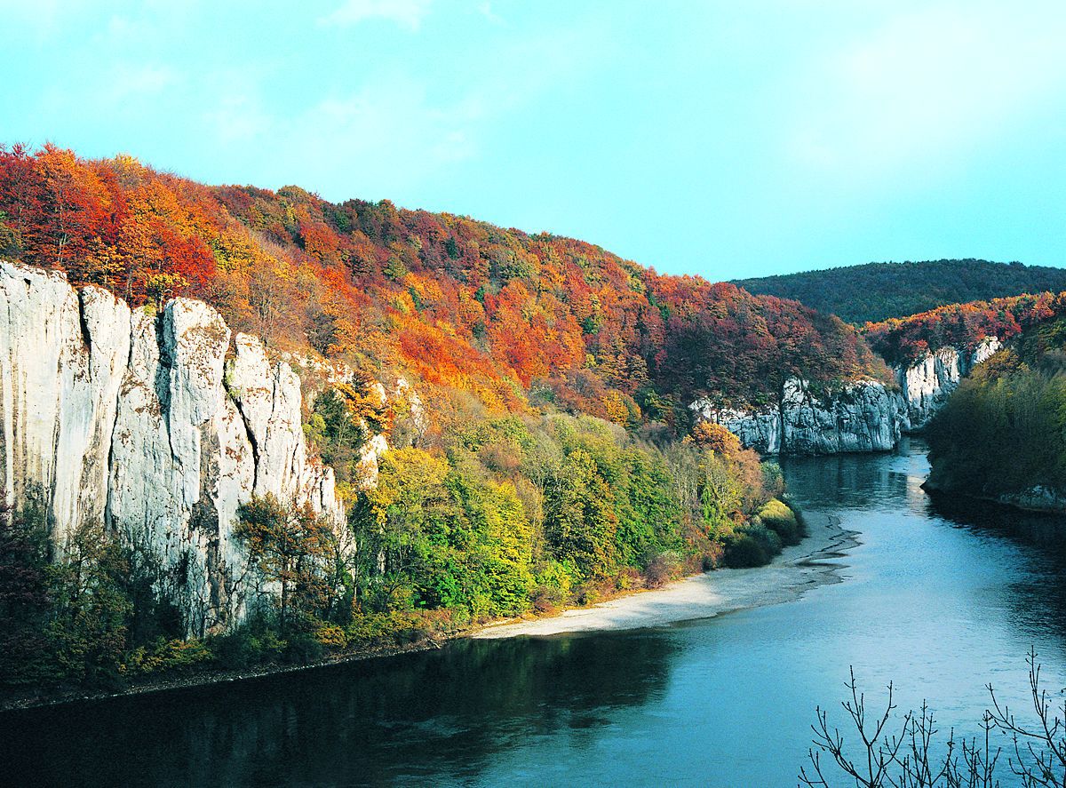 Felswände mit einem bunten Herbstwald ragen über einem mäandernden Fluss auf (Foto: Wolfgang Willner)