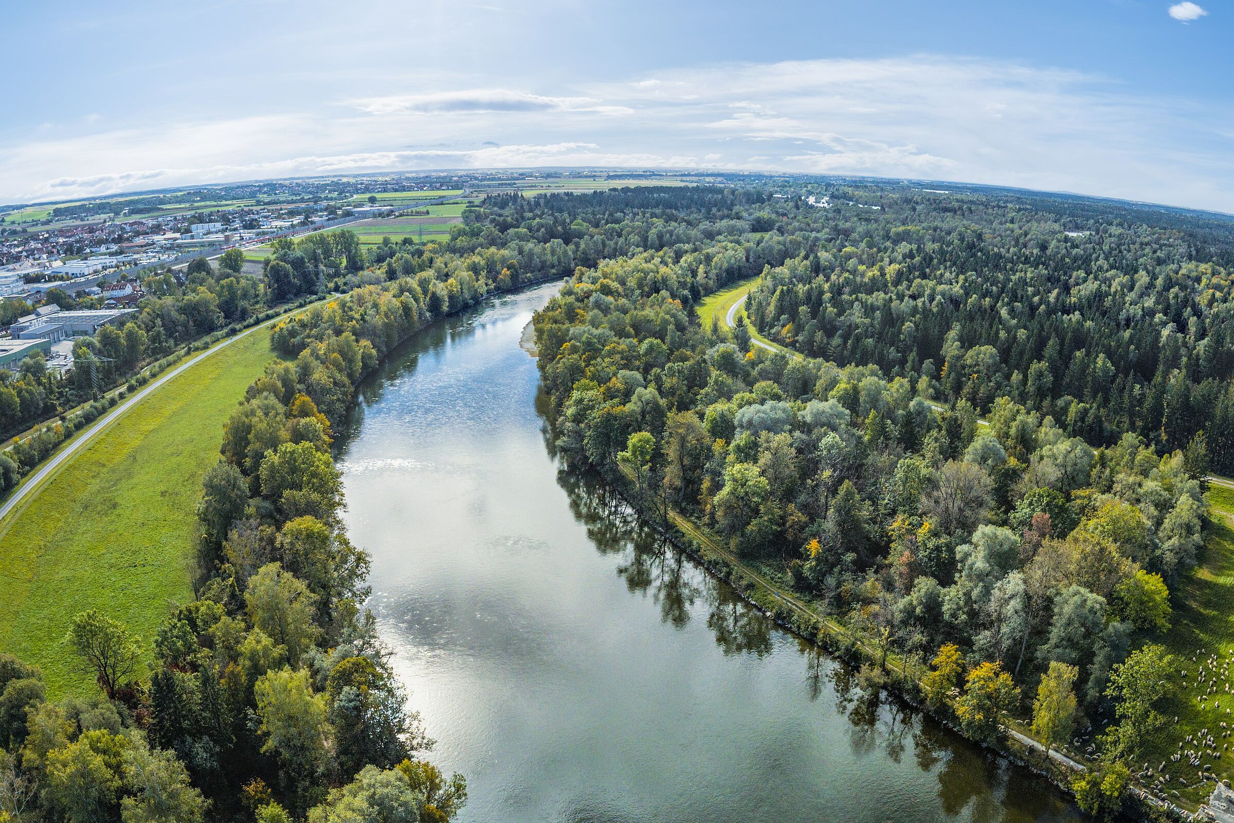 Ein Fluss fließt in großem Bogen durch Wälder, am Rand sind Häuser zu sehen. (ARochau/stock.adobe.com) 