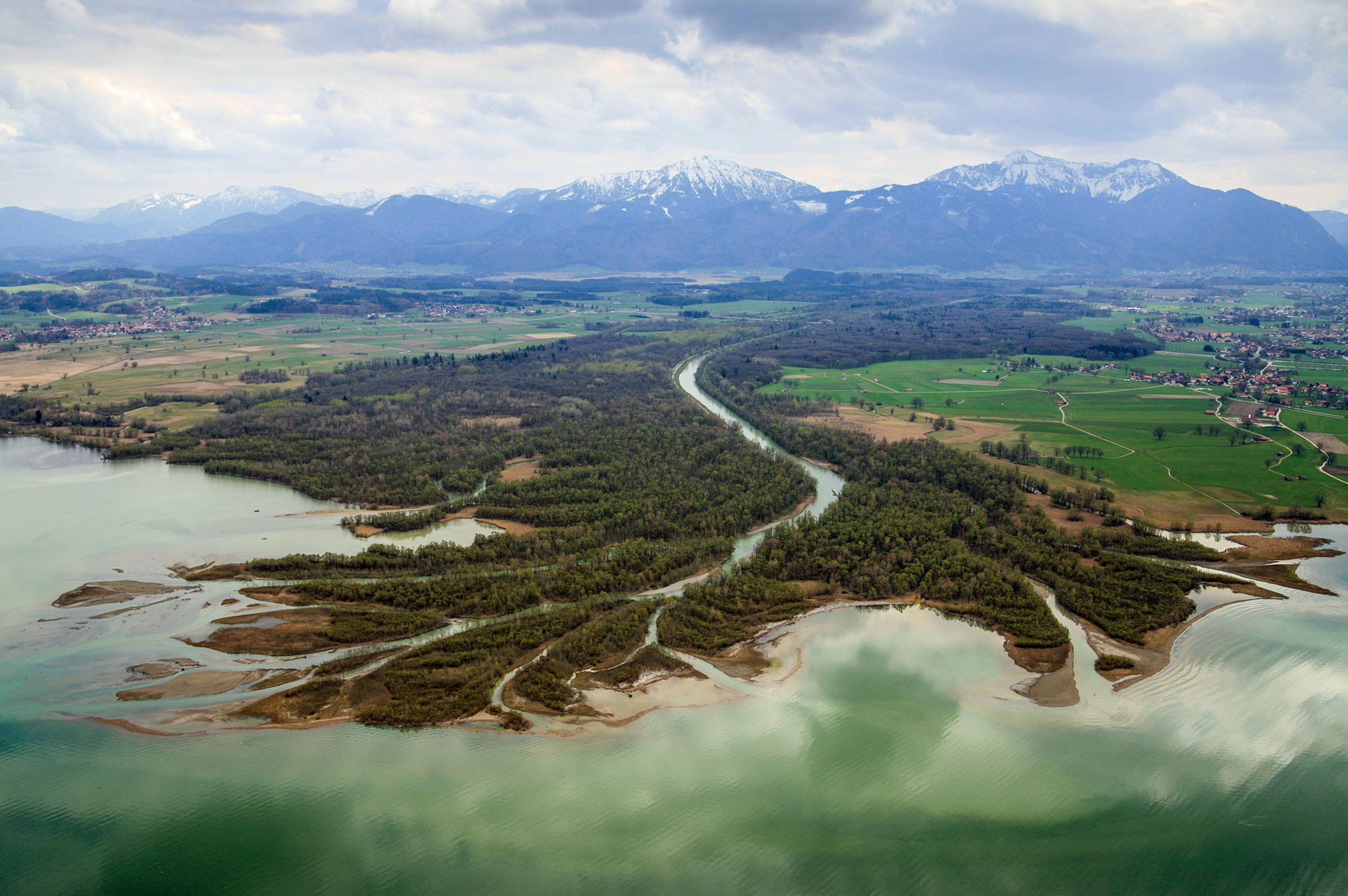 Ein Fluss fließt auf einen türkisfarbenen See zu und teilt sich an der Mündung in viele Seitenarme auf, im Hintergrund schneebedeckte Berge (Foto: Klaus Leidorf) 
