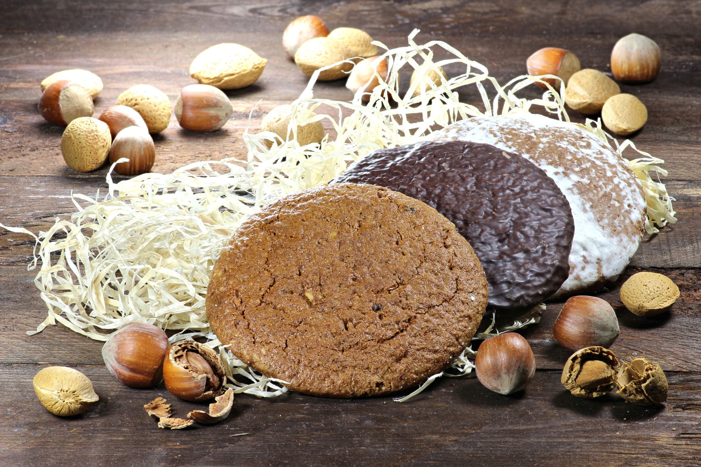 Drei Lebkuchen liegen auf Holzwolle, drumherum liegen Nüsse. (Björn Wylezich/fotolia.com)