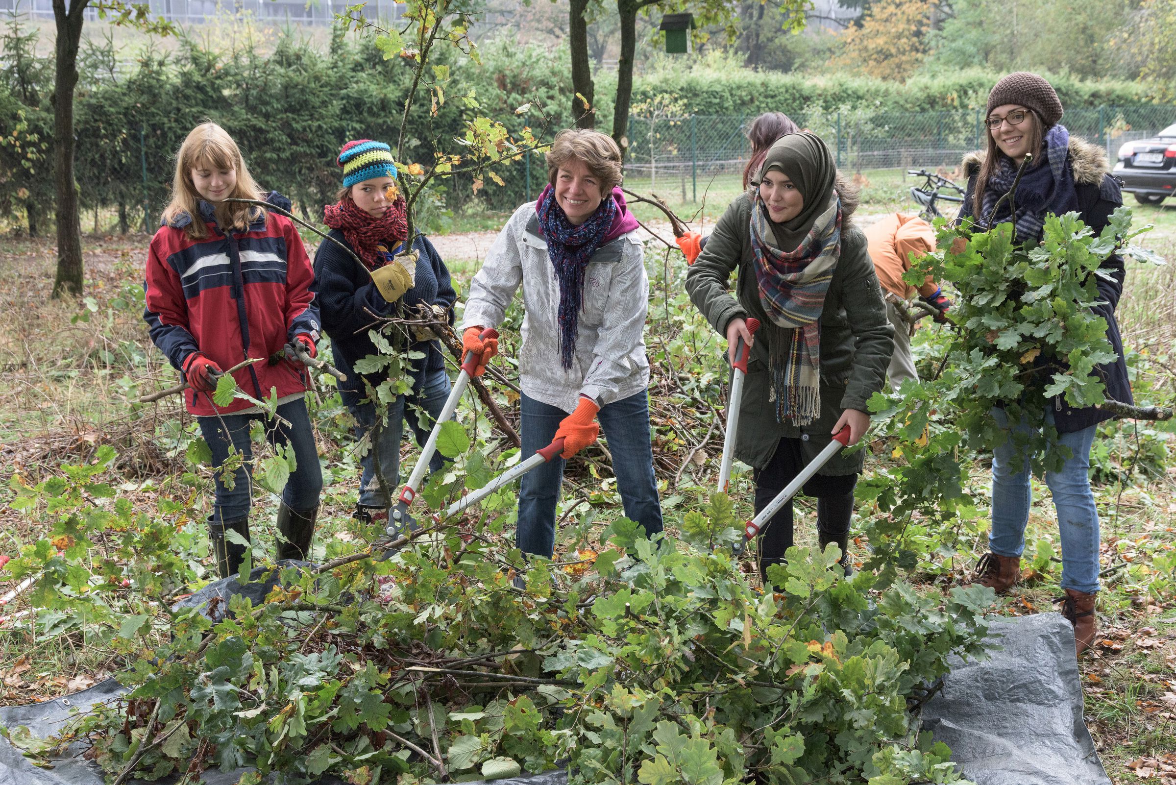 Naturschutz in der Stadt darf auch Spaß machen: Eine Gruppe Jugendlicher und eine Erwachsene zerkleinern mit großen Zangen Äste. (Foto: Toni Mader)