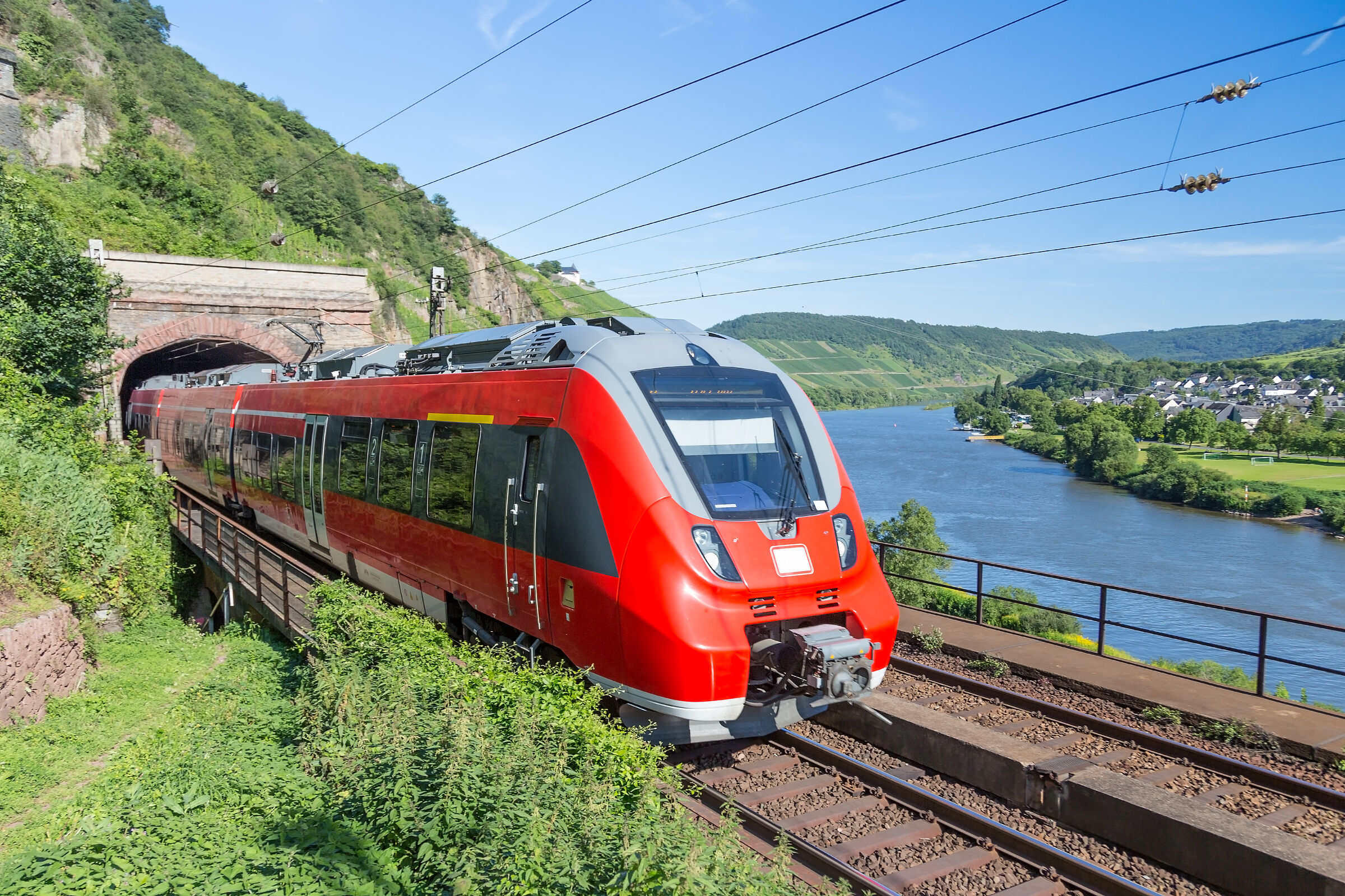Regionalbahn fährt am Flussufer aus einem Tunnel (Foto: Kruwt - stock.adobe.com)