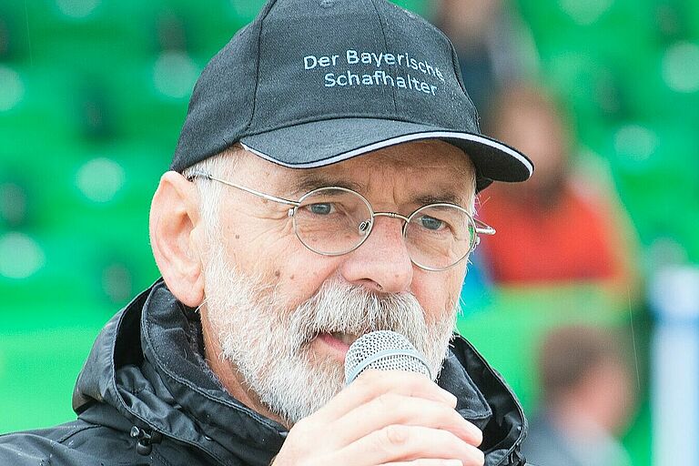Schafhalter Rene Gomringer spricht mit Mikrofon in der Hand. Der ehemalige Geschäftsführer des Bayerischen Schafhalterverbandes ist ein großer Verfechter eines guten Herdenschutzes. (Foto: Doris Sebald)