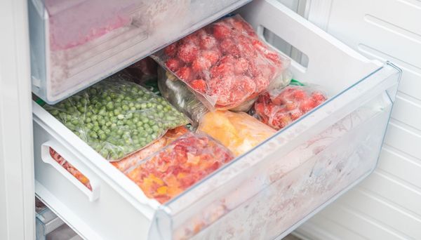 Lebensmittel konservieren: Beutel mit eingefrorenem Gemüse liegen im Fach einer Gefriertruhe.