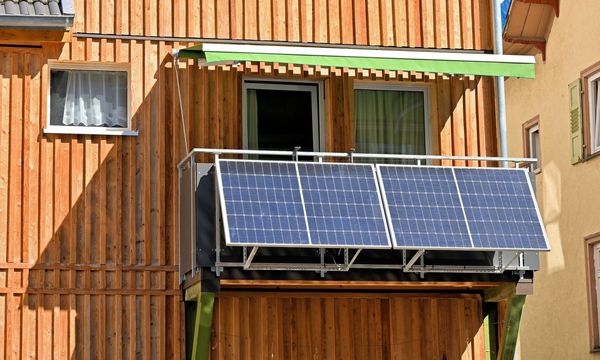 Balkonsolarkraftwerk an einem sonnigen Balkon eines Hauses mit Holzfassade (Foto: reimax16/stock.adobe.com)