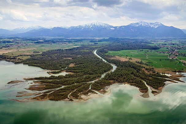 Ein Fluss fließt auf einen türkisfarbenen See zu und teilt sich an der Mündung in viele Seitenarme auf, im Hintergrund schneebedeckte Berge (Foto: Klaus Leidorf)