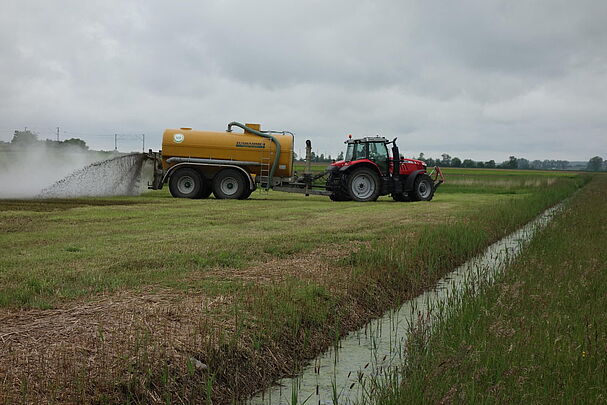Ein Traktor verteilt auf einer Wiese Gülle neben einem Wasserlauf. Durch zu viel Gülle erhöhen sich die Nitratwerte im Grundwasser. (Foto: Marion Ruppaner)