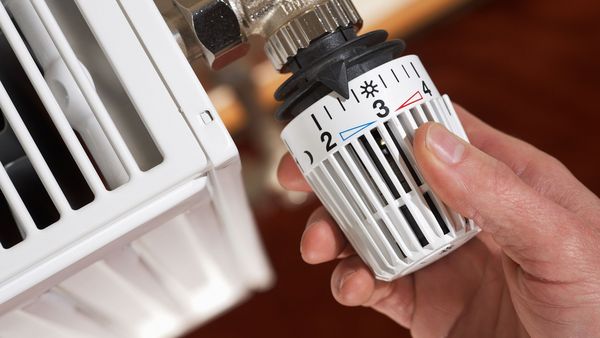 Richtig heizen: Eine Hand dreht den Thermostat an einer Heizung auf die passende Temperatur.