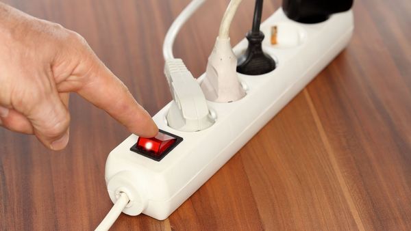 Stand-By vermeiden: Mann schaltet Steckerleiste aus.