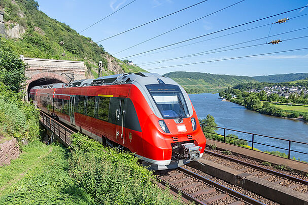 Regionalbahn fährt am Flussufer aus einem Tunnel (Foto: Kruwt - stock.adobe.com)