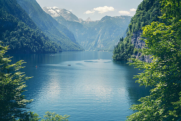 Blick auf einen tiefblauen See umgeben von steilen, bewaldeten Bergen. Im Hintergrund verschneite Gipfel. (Foto: Serkat/fotolia.com)