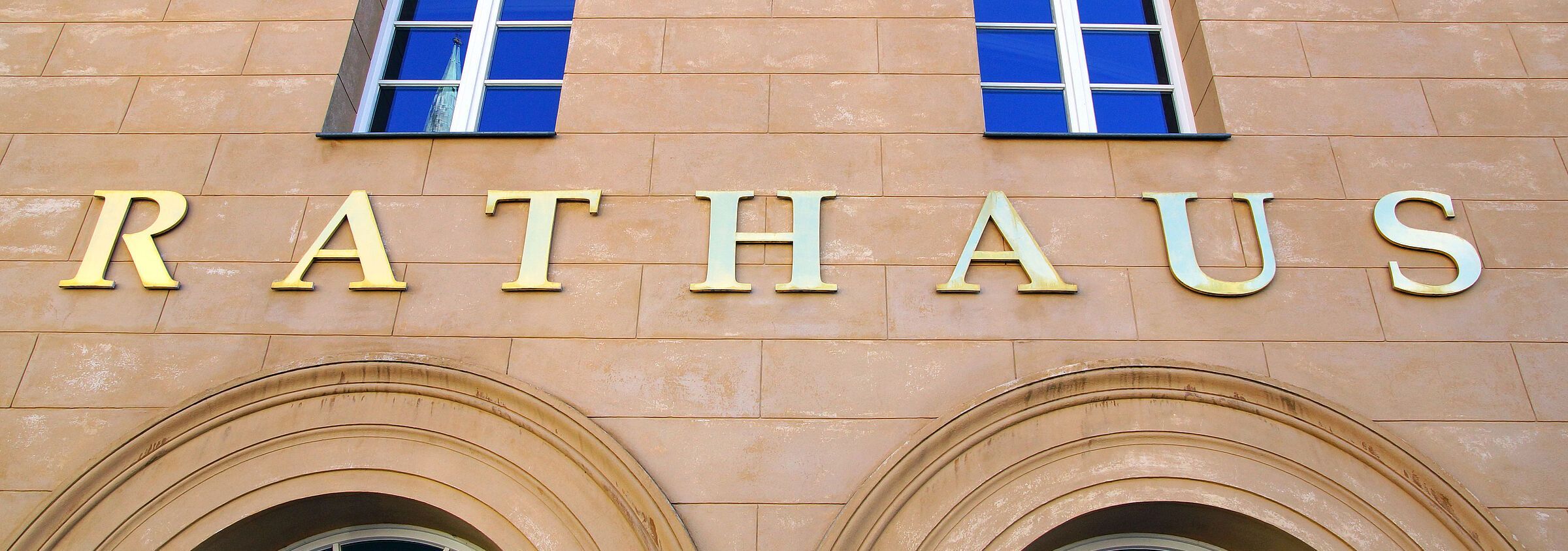 An einem Gebäude hängt ein goldfarbener Schriftzug "Rathaus"