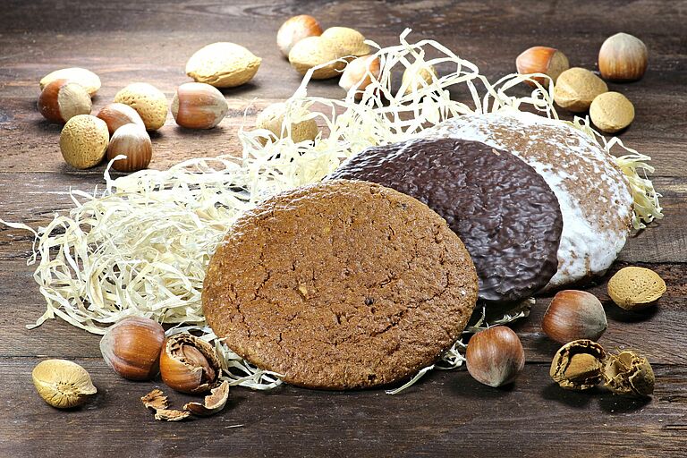 Drei Lebkuchen liegen auf Holzwolle, drumherum Nüsse. (Foto: fotolia.com/Björn Wylezich)