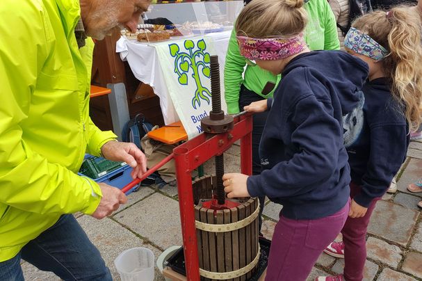Kind presst zusammen mit einem Helfer des BN Apfelsaft an einer Kelter