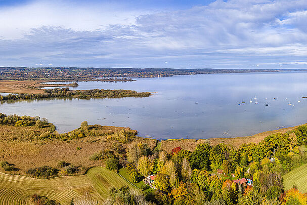 Ein See, am Ufer wechseln sich Wiesen und Wälder ab
