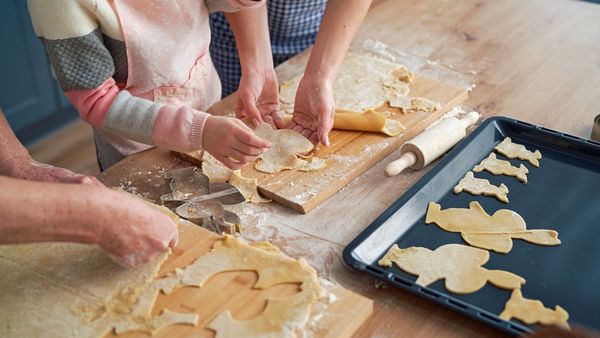 Ostern nachhaltig feiern: Eine Familie backt gemeinsam Osterkekse in Form von Hasen.