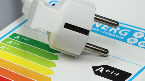 Energieeffeziente Elektrogeräte: Label mit Energieeeffizienzklasse A, darauf liegt ein Stromstecker.